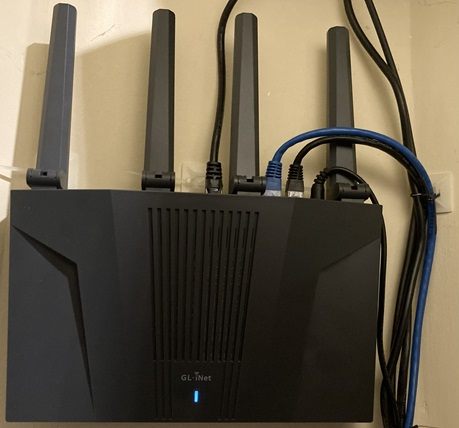 An der Wand montierter GL-iNet Router mit sauberer Verkabelung